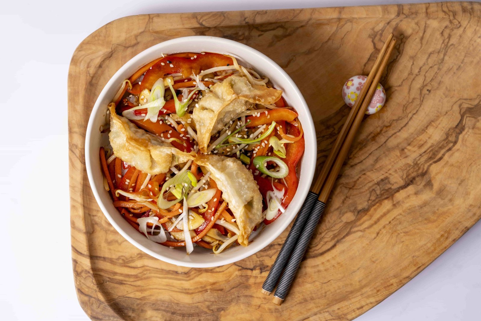 Bol de donburi végétarien avec saumon et avocat, accompagné de salade de chou et sauce crémeuse, présenté sur un plateau en bois avec des baguettes.